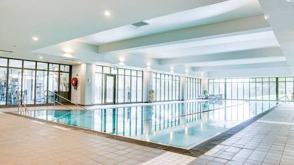 Indoor swimming pool with tiled surround and full-height glazing